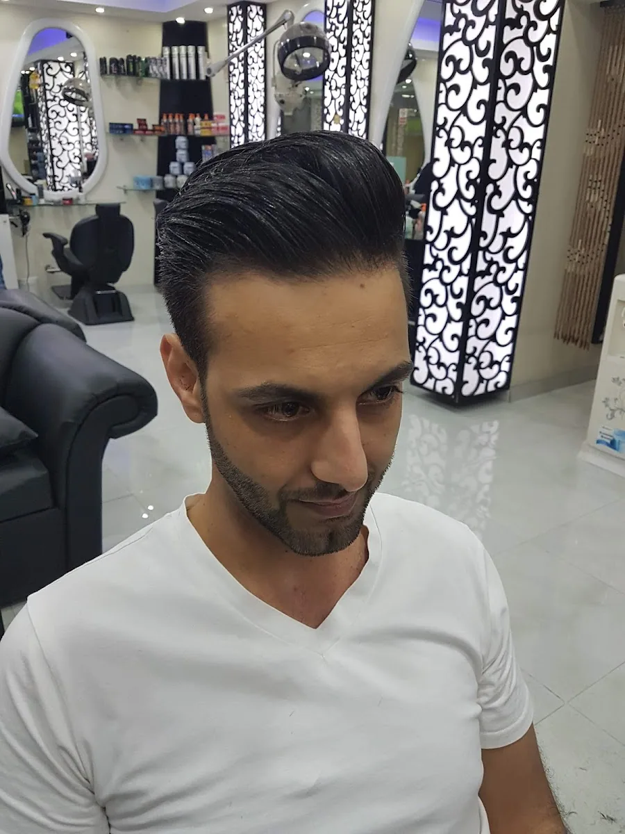 Client with a slicked-back style in front of the salon's lit scrollwork pillars