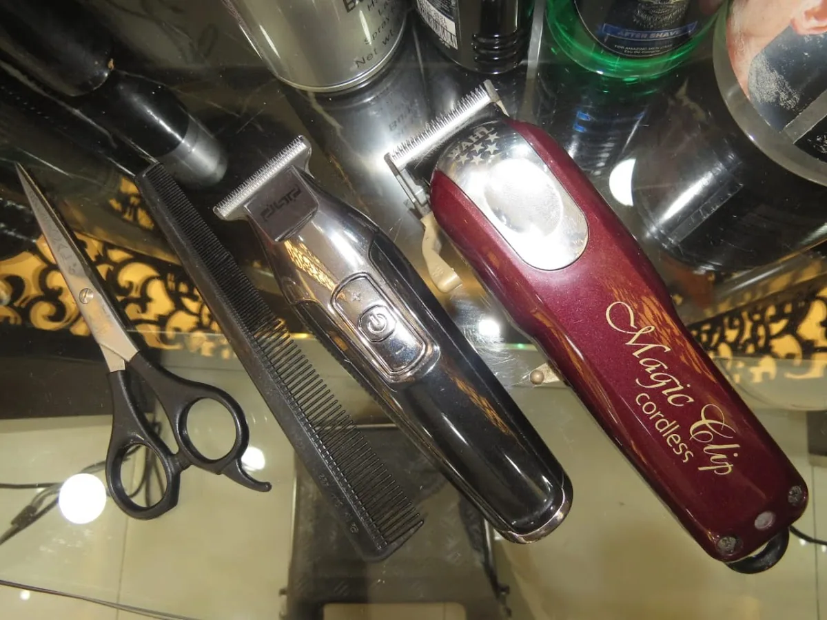 Barber scissors, comb, trimmer and a Wahl cordless clipper on a glass shelf