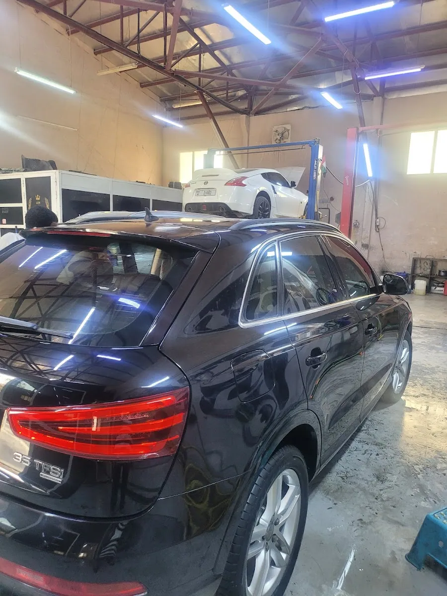 The reflective mirror finish on a freshly polished black Audi inside the workshop