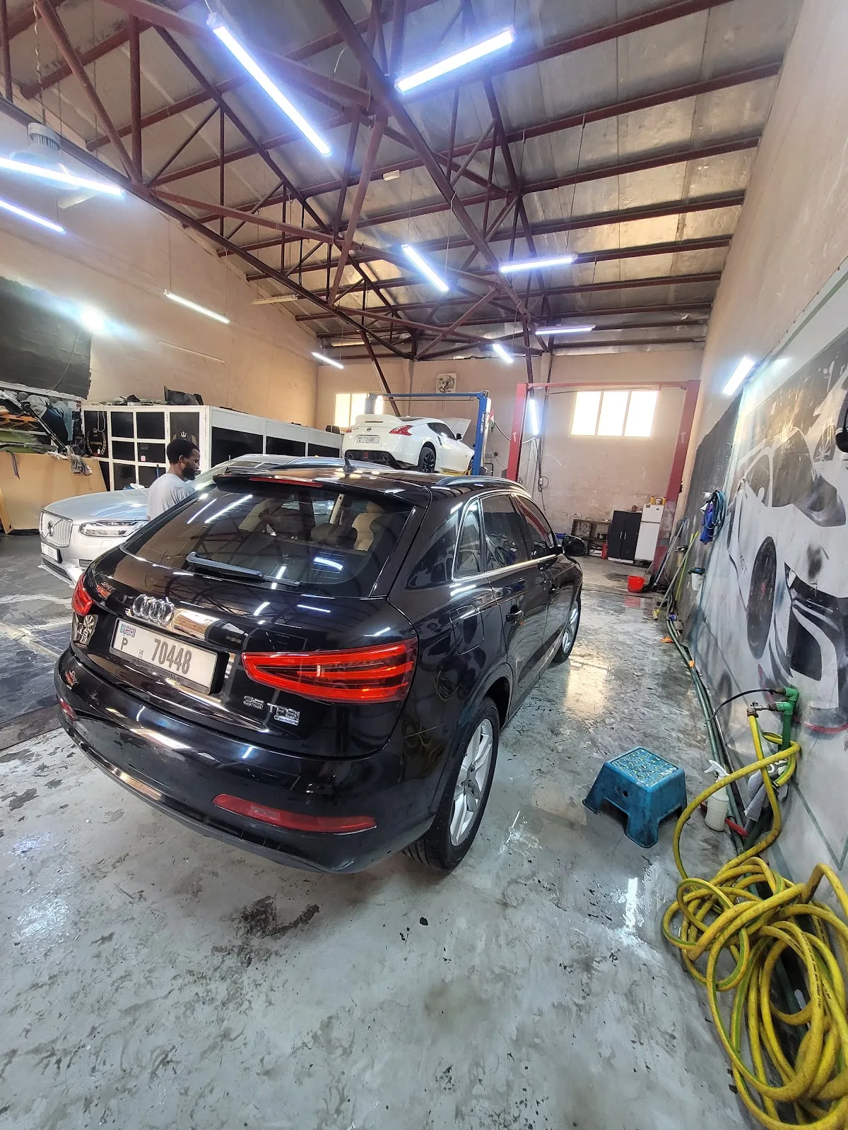 Inside the H&M Car Polishing workshop in Al Quoz with a black Audi and a sports car on the lift
