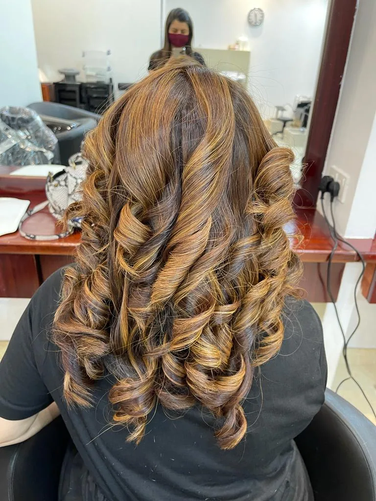 Glossy caramel highlights and curls created in the colour chair