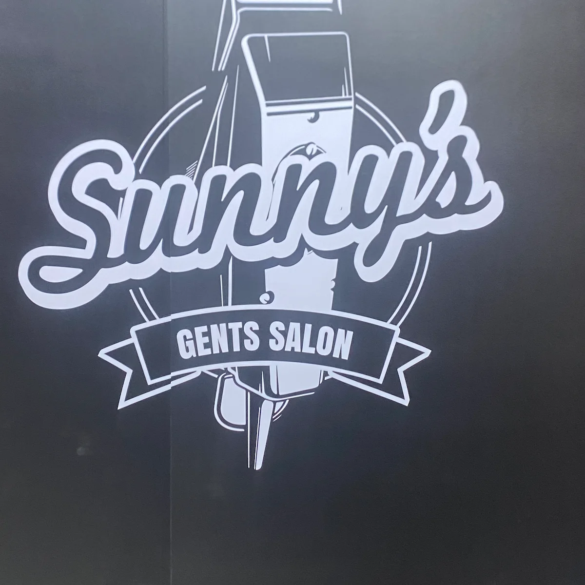 Close-up of the Sunny's Gents Salon vintage clipper emblem