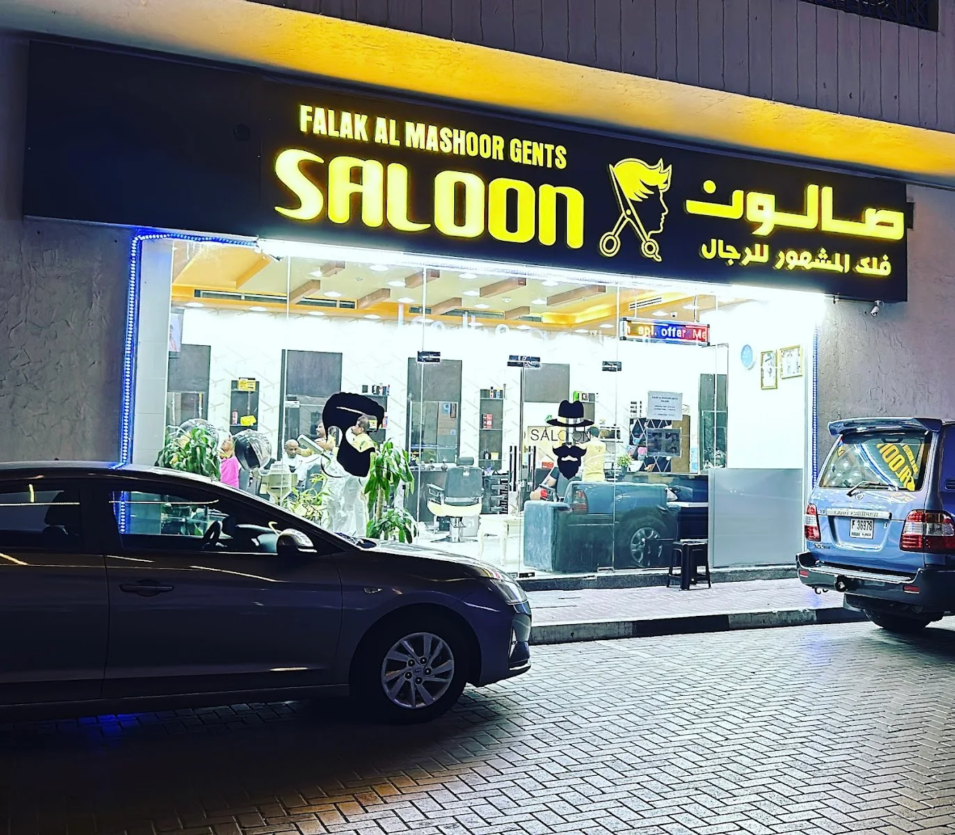 Falak Al Mashoor Gents Salon storefront lit up at night in Al Nahda, Dubai