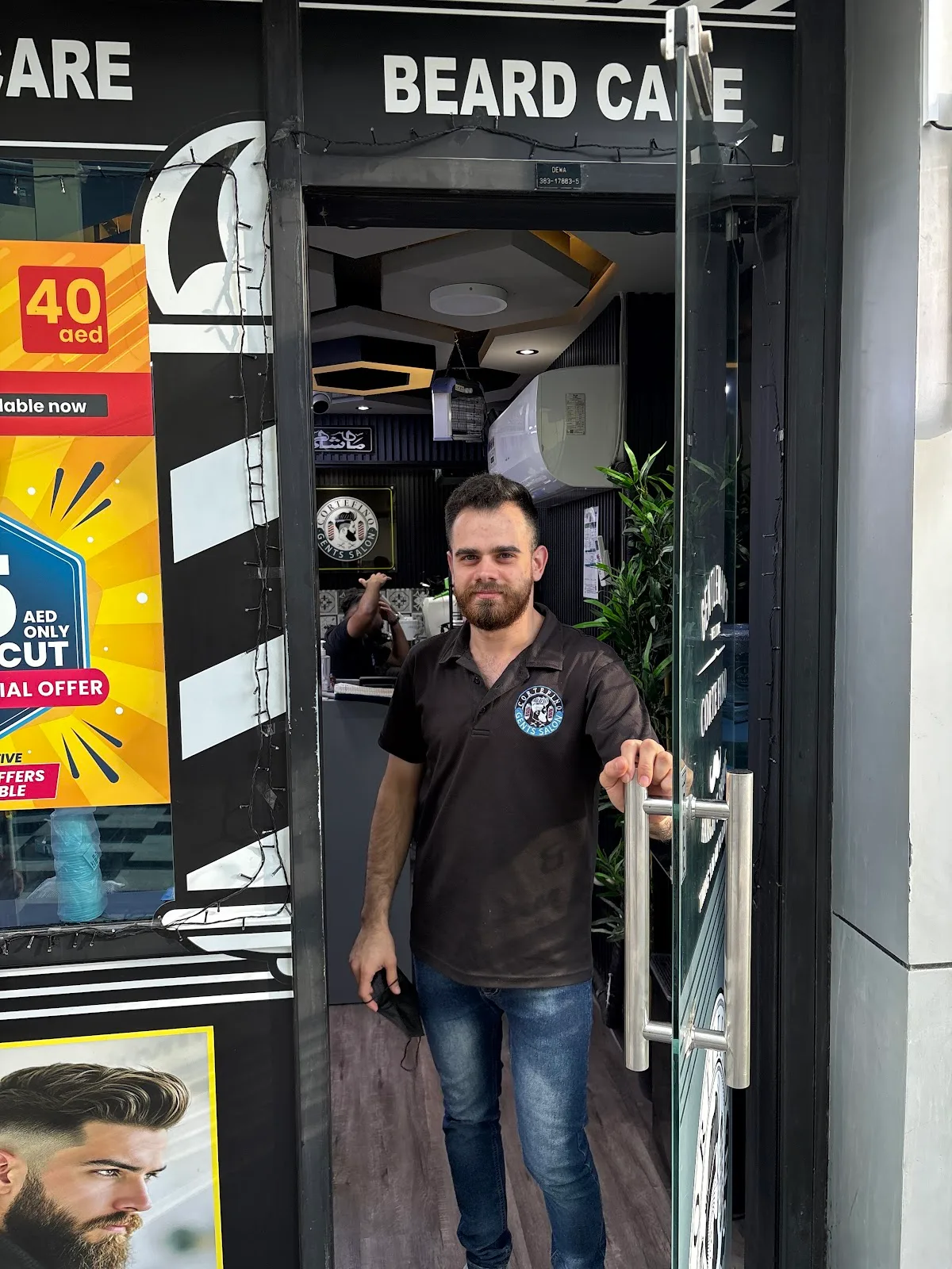 A CorteFino barber holding open the glass beard care entrance to the salon
