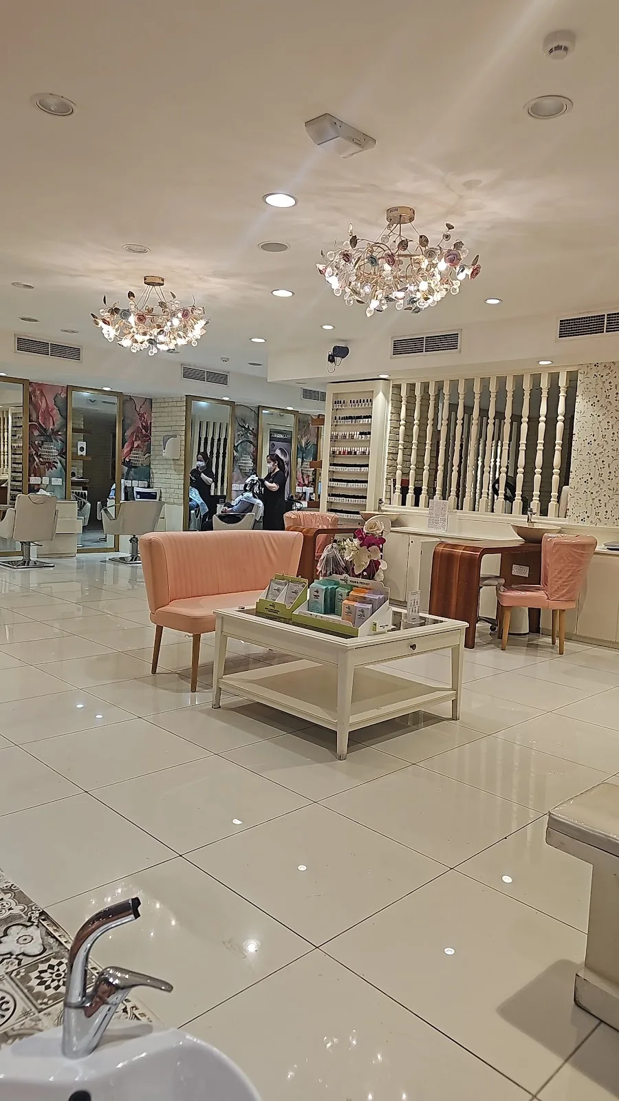 The cream-toned lounge inside Ricky's Ladies' Salon with chandeliers and styling stations