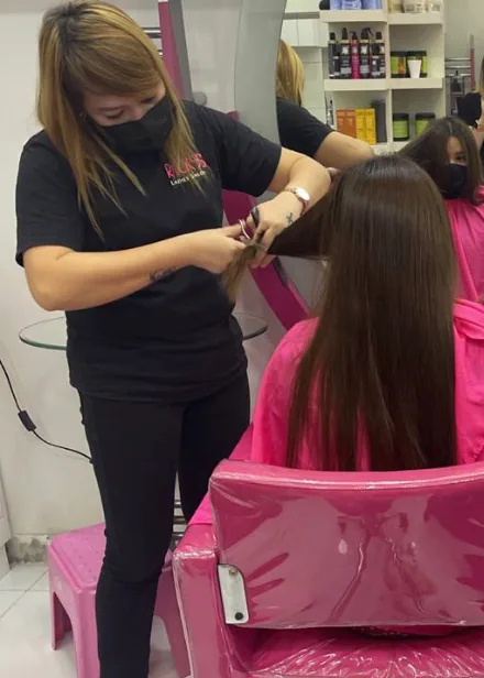 A stylist sectioning a client's long hair at Ricky's Ladies' Salon