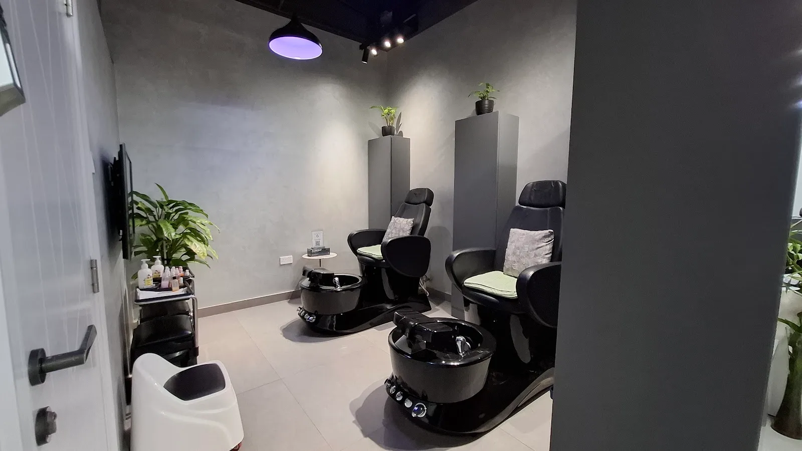A quiet grooming and foot-spa room with two black chairs and plants