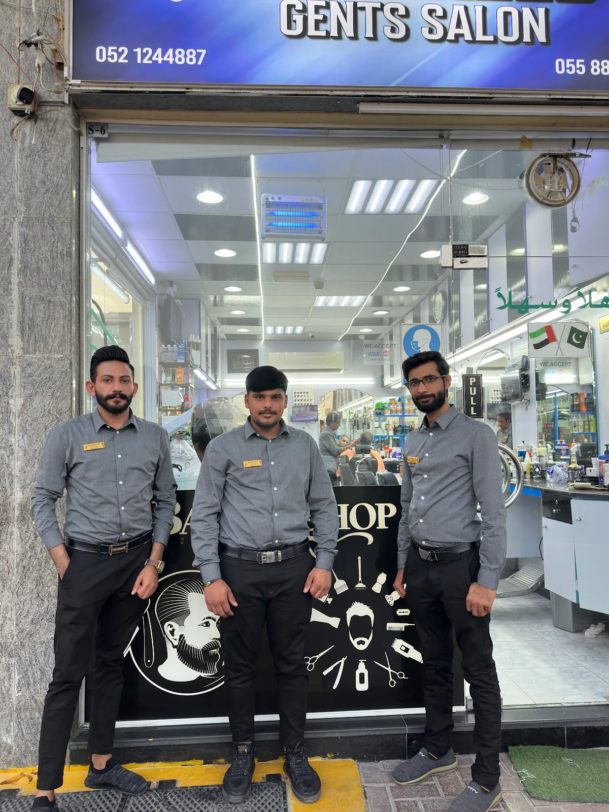 The Yathreeb Gents Salon team in grey shirts outside the shopfront