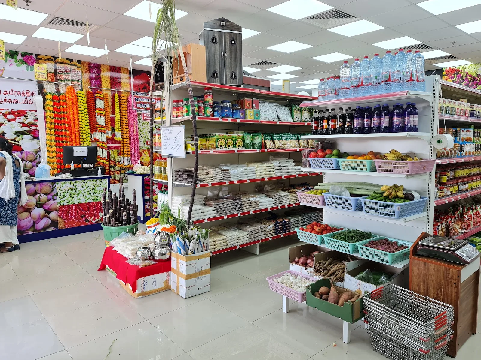 Inside Perumal Flowers showing the garland counter, grocery shelves and fresh produce