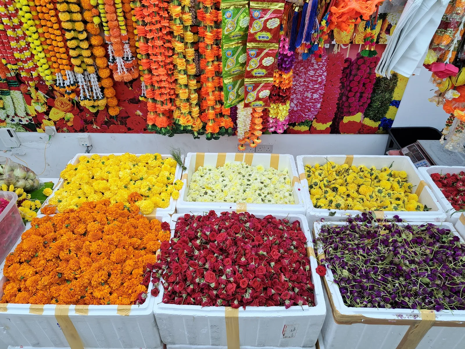 Trays of loose marigold, rose, chrysanthemum and purple flowers