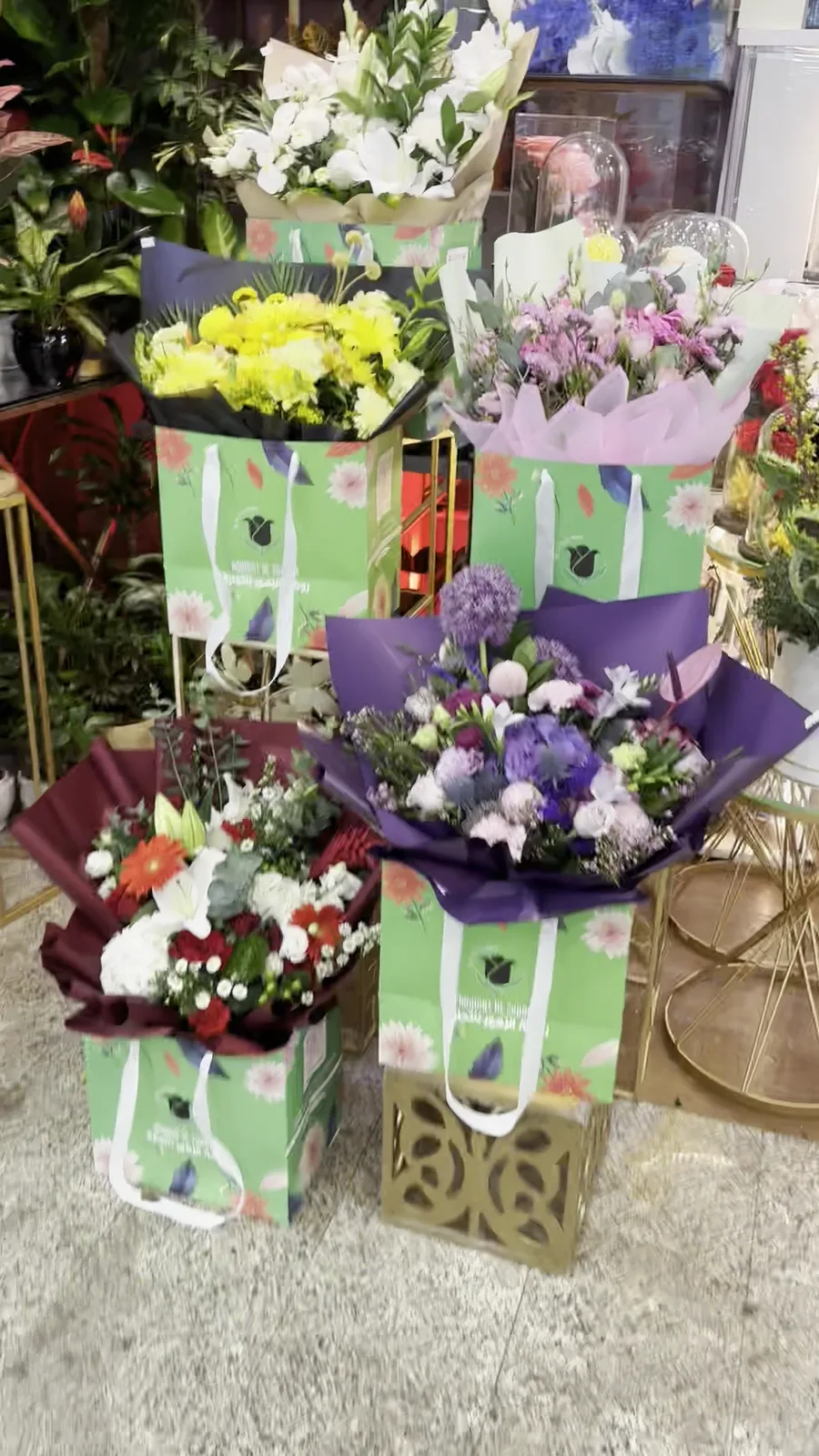 Several bouquets in green Rowdat Al Zuhoor branded gift bags