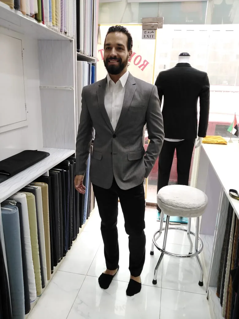 Tailored grey jacket and rolls of suiting fabric inside Al Aryam Tailoring