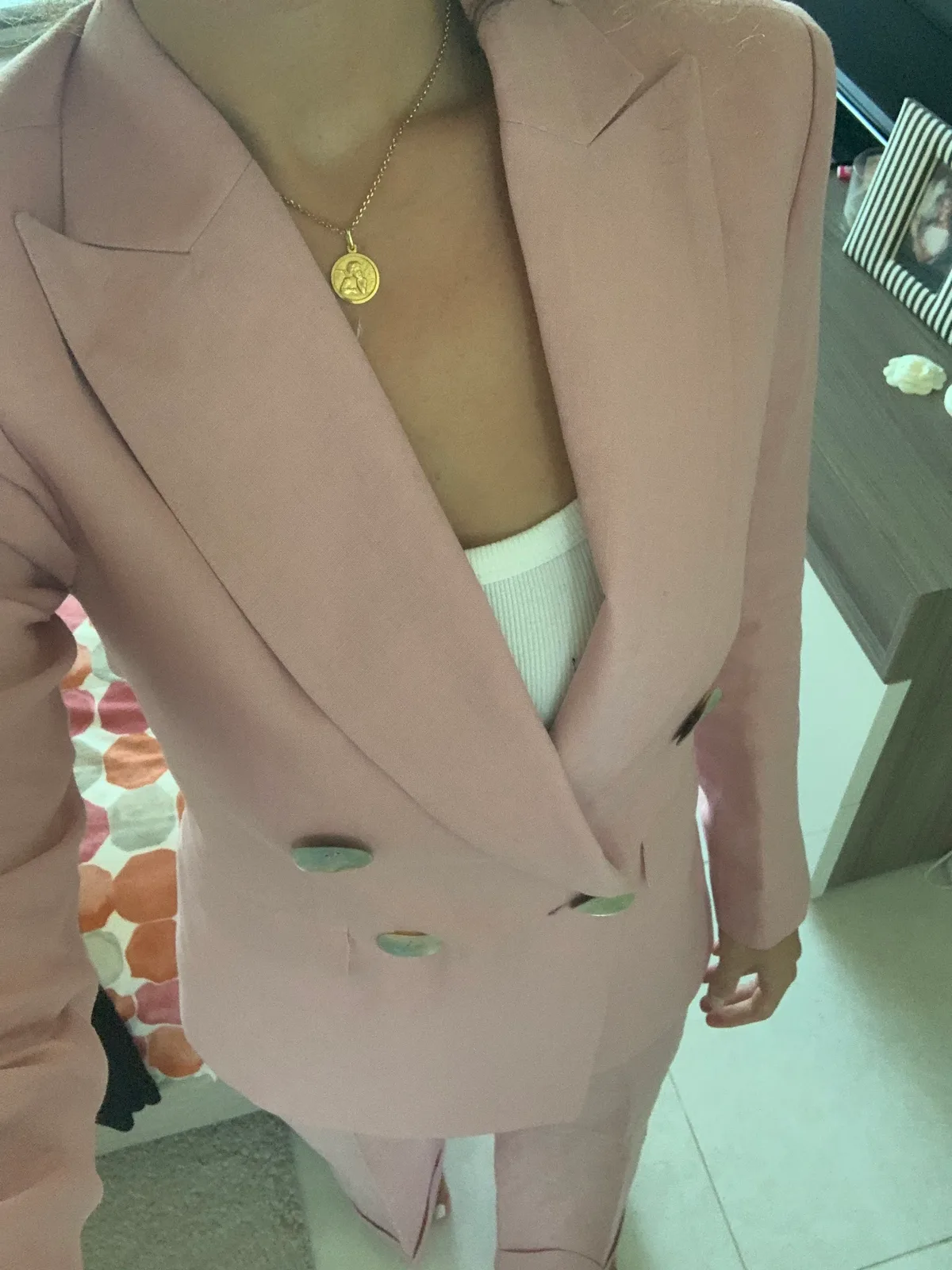 Close-up of lapel and button detail on a pale pink tailored jacket