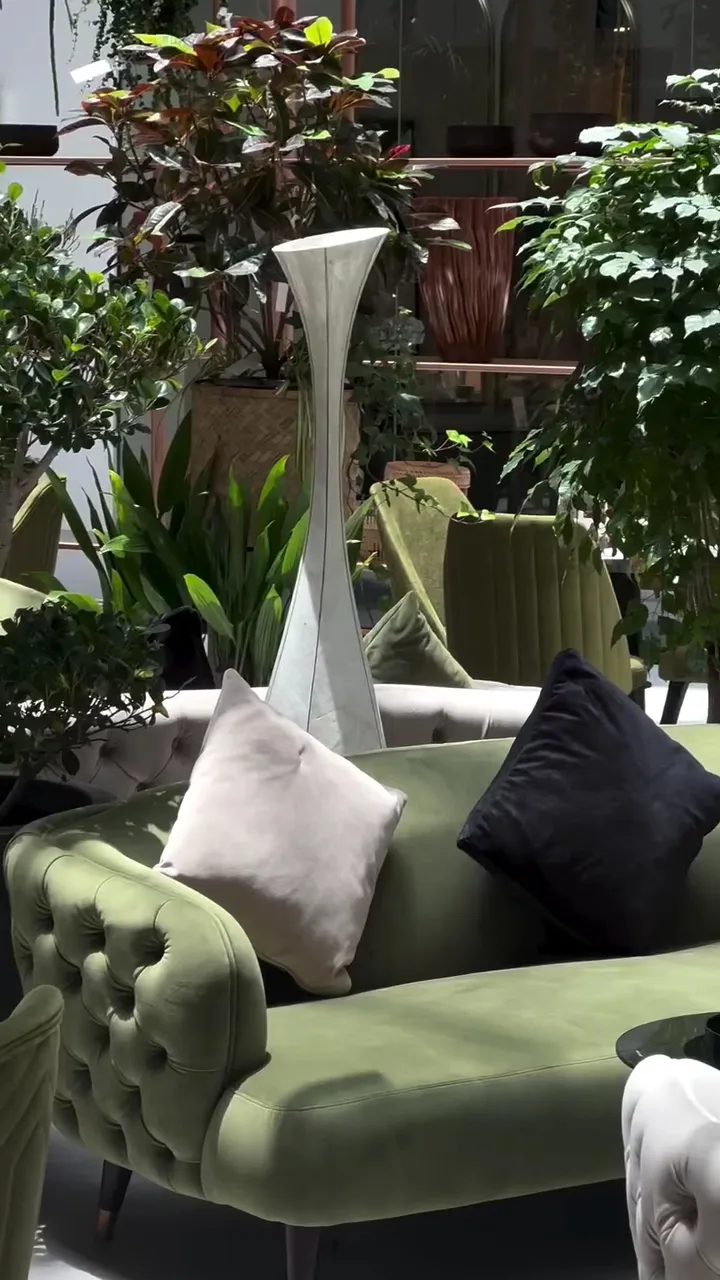 A green velvet sofa styled among tall plants in the Folivana showroom