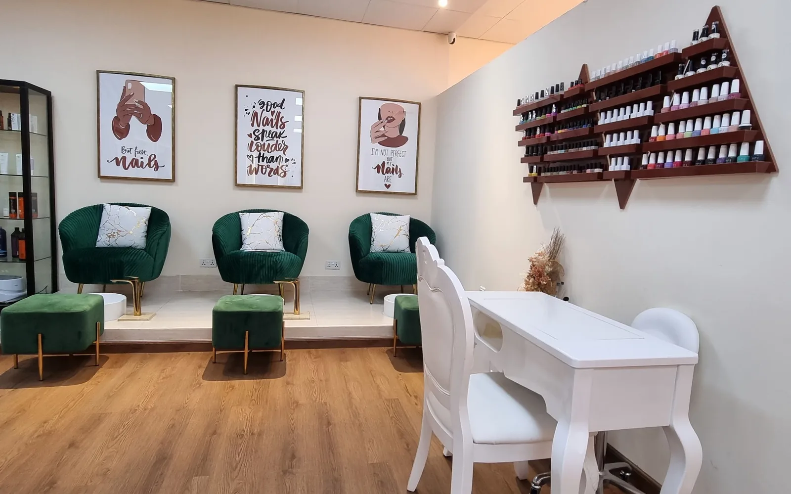 The salon's nail bar with green velvet chairs and polish wall