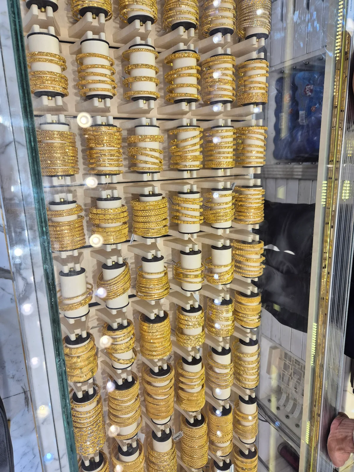 Rows of 22K gold bangles stacked in a display case at Khushboo Jewels