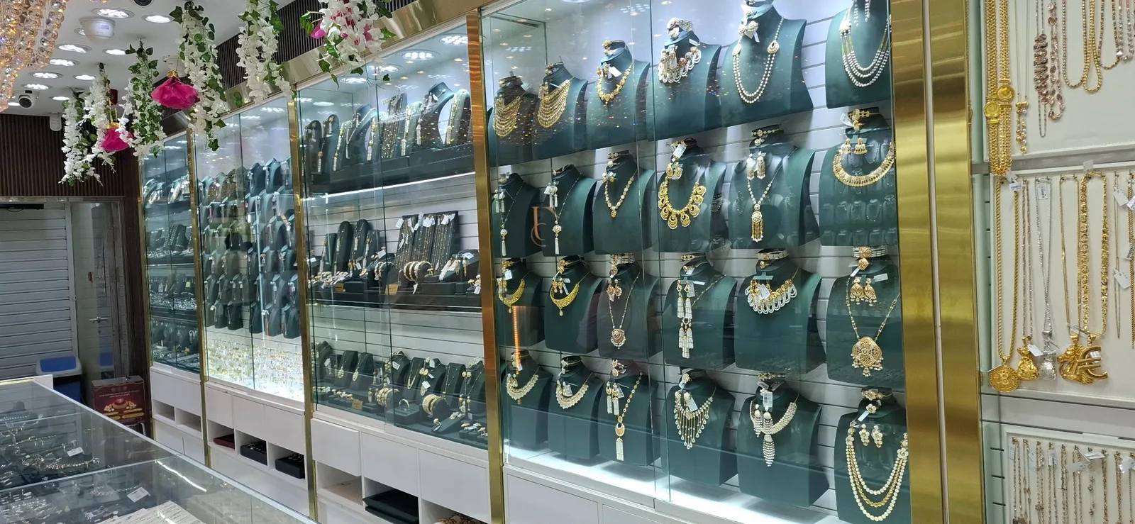 Wall of gold necklaces and bridal sets displayed on green busts inside Khushboo Jewels