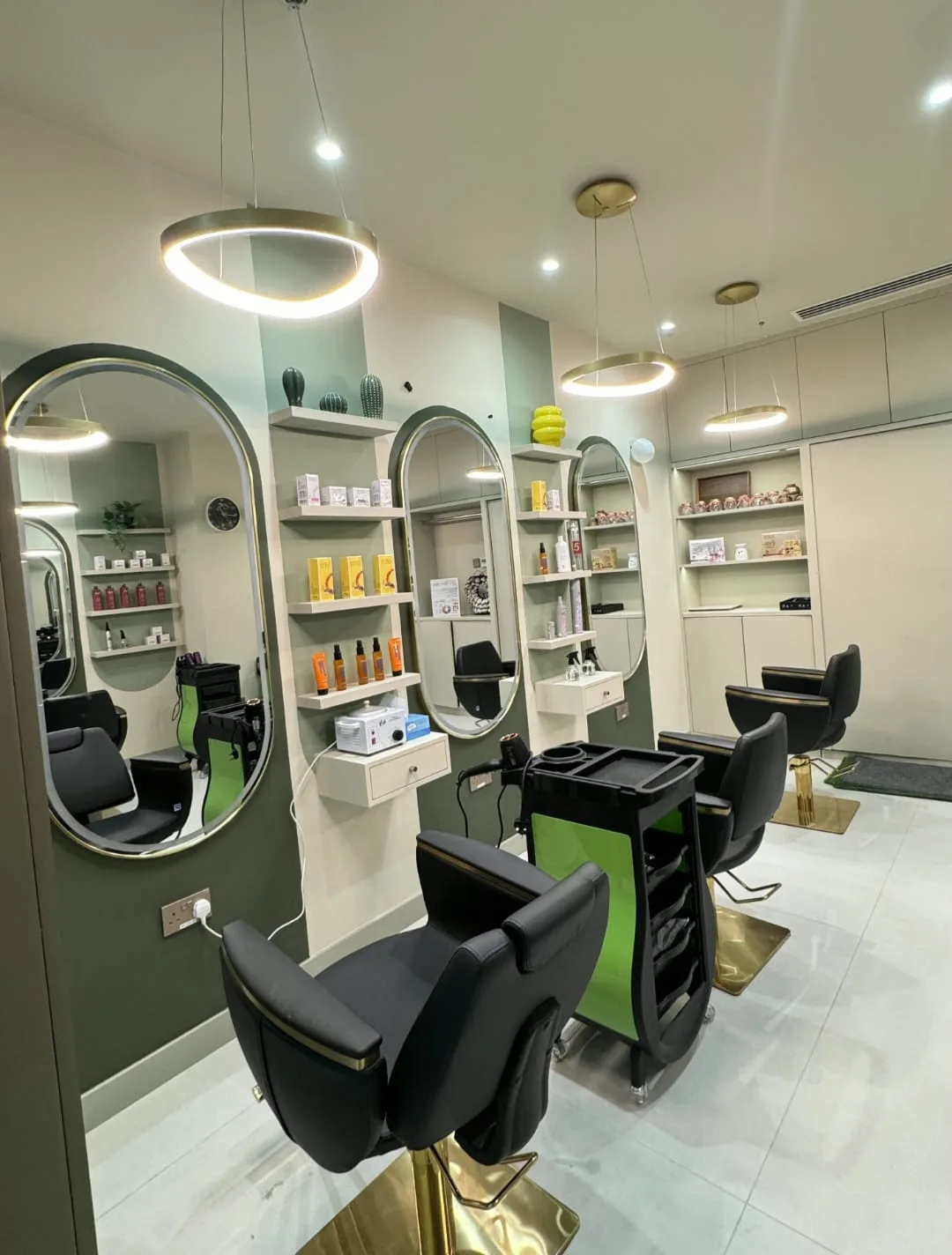 Styling stations at Zaaya Beauty Salon with oval gold-framed mirrors, ring lights and black-and-gold chairs