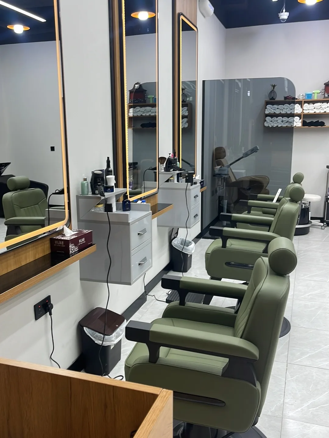 Row of olive leather barber chairs and lit mirrors at BOYKA