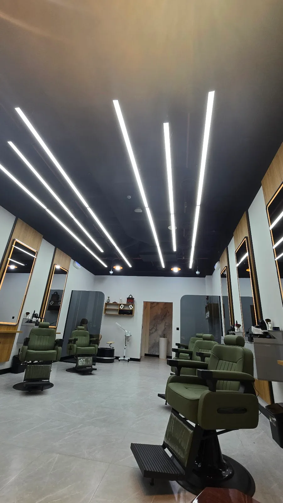 BOYKA Gents Salon interior with dramatic linear ceiling lighting and olive barber chairs