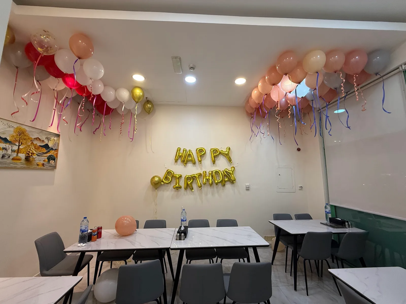 A room styled with pink and gold balloon garlands and a Happy Birthday foil banner
