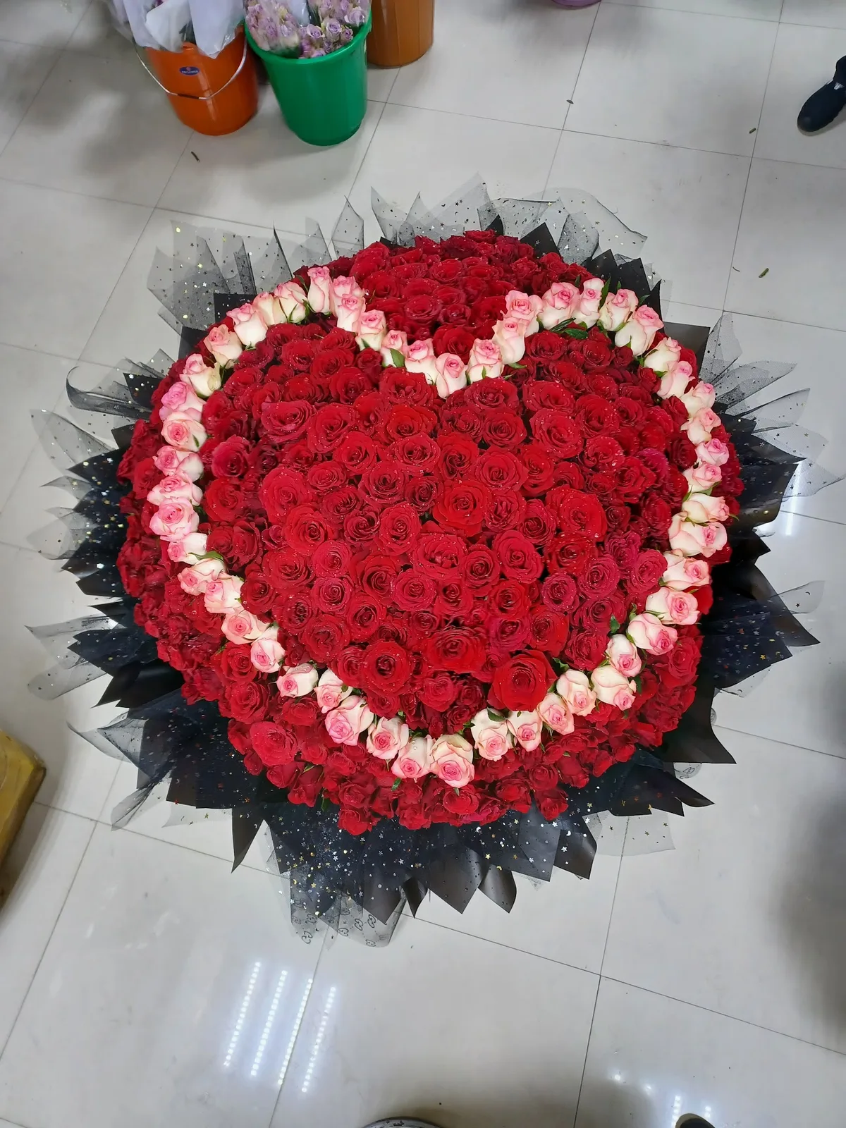 A large heart-shaped arrangement of red roses ringed with blush pink roses, made by Red Lantern Flowers