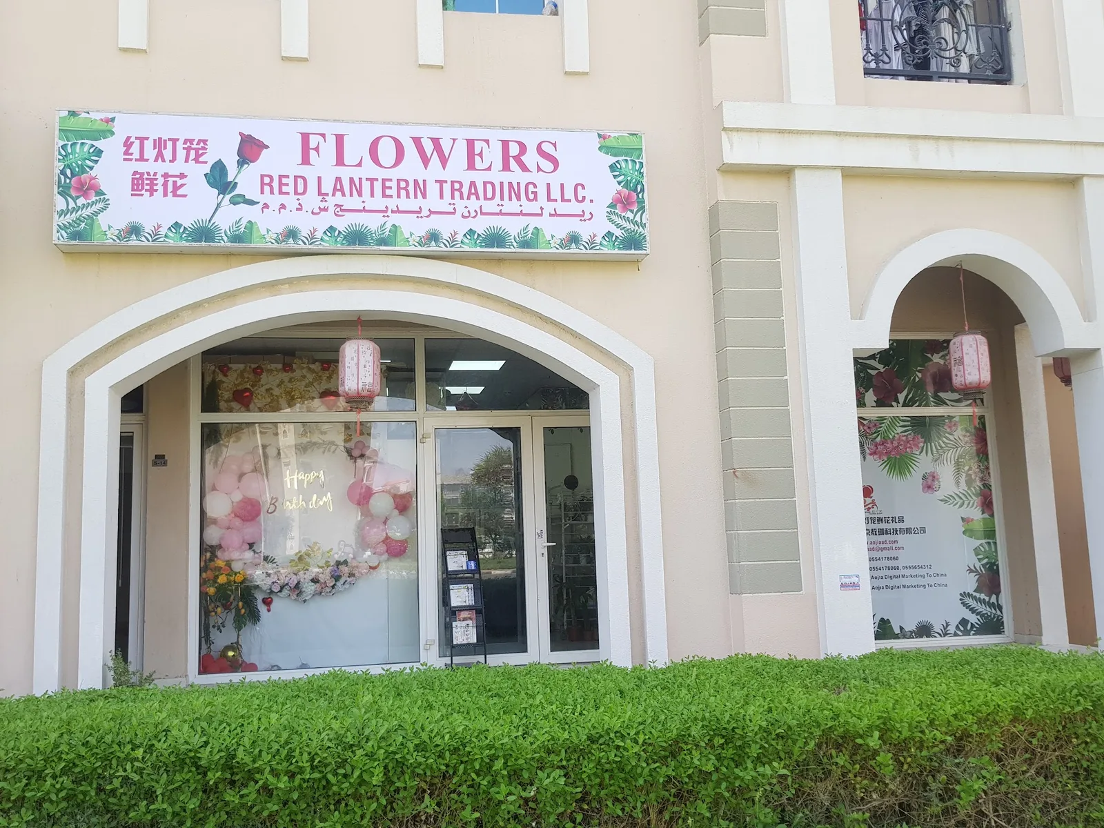 The Red Lantern Trading LLC storefront in France Cluster, Dubai, with a floral sign and pink lanterns