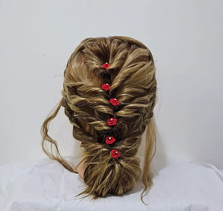 An intricate braided bridal updo finished with red rose accents