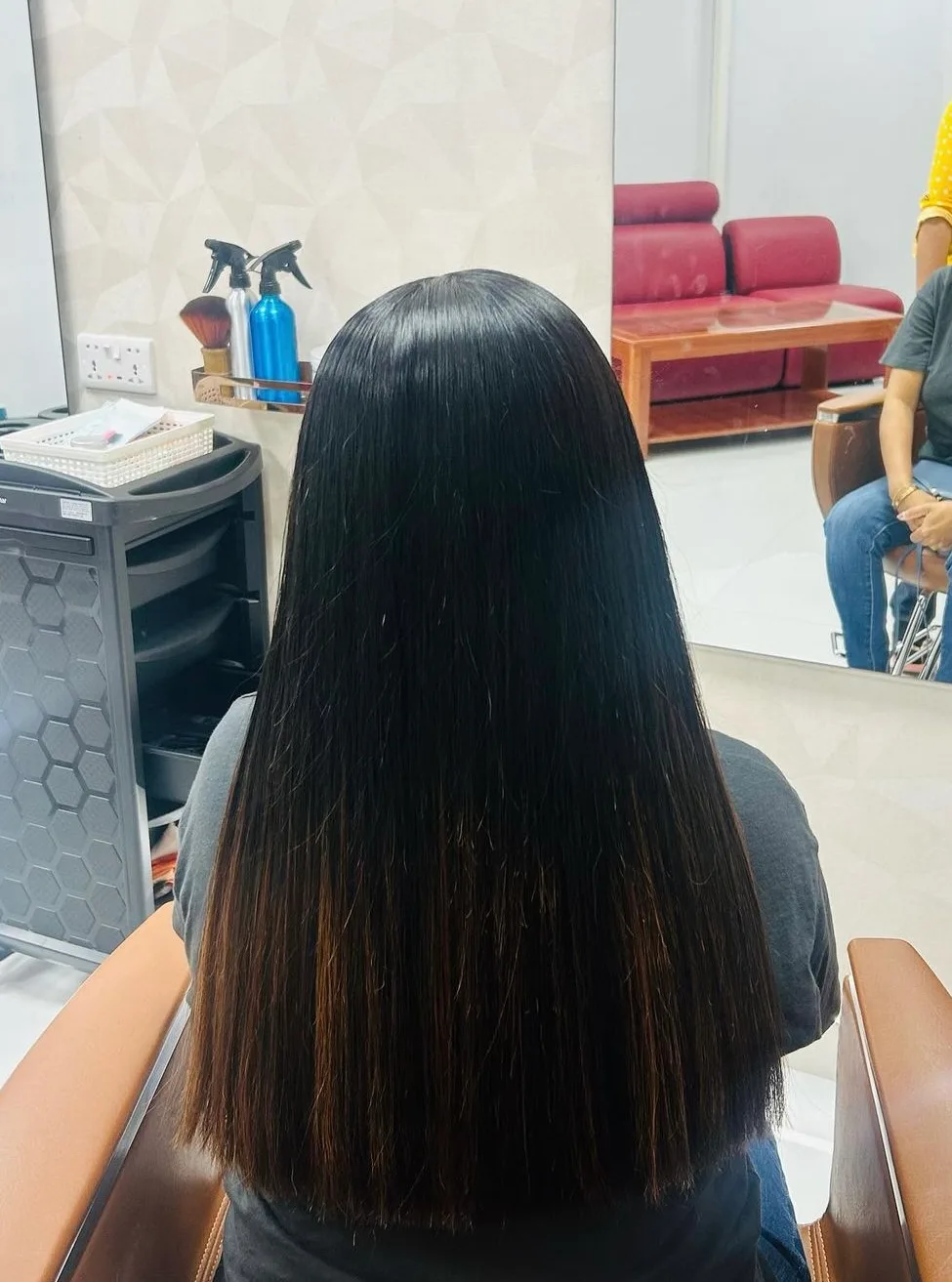 Long dark hair styled to a glossy, smooth blow-dry finish at the salon