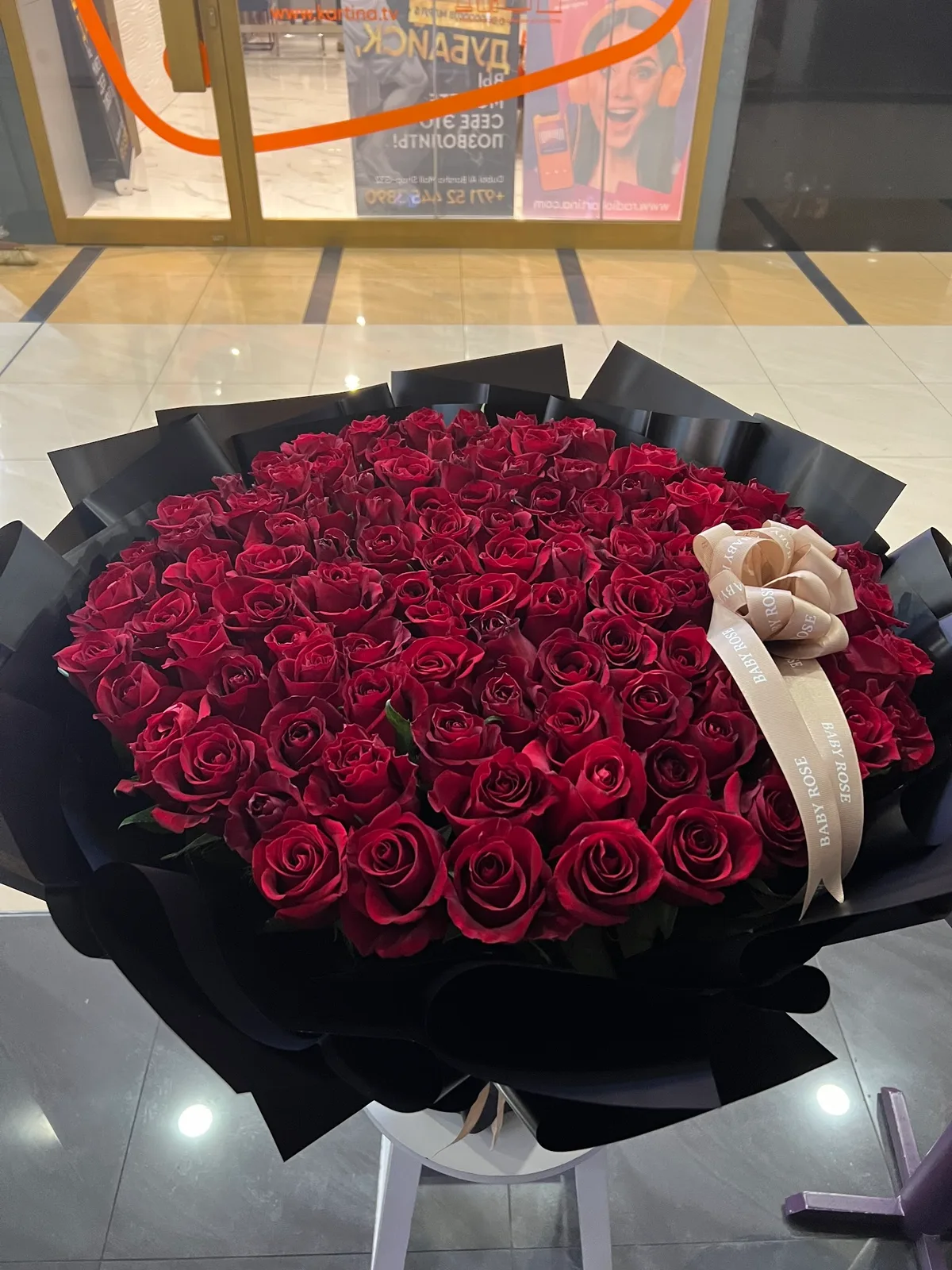 A large round bouquet of deep red roses finished with a cream Baby Rose ribbon