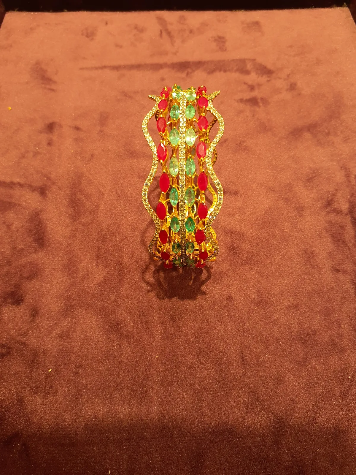 Gold bangle set with rows of red and green marquise gemstones and clear pavé stones
