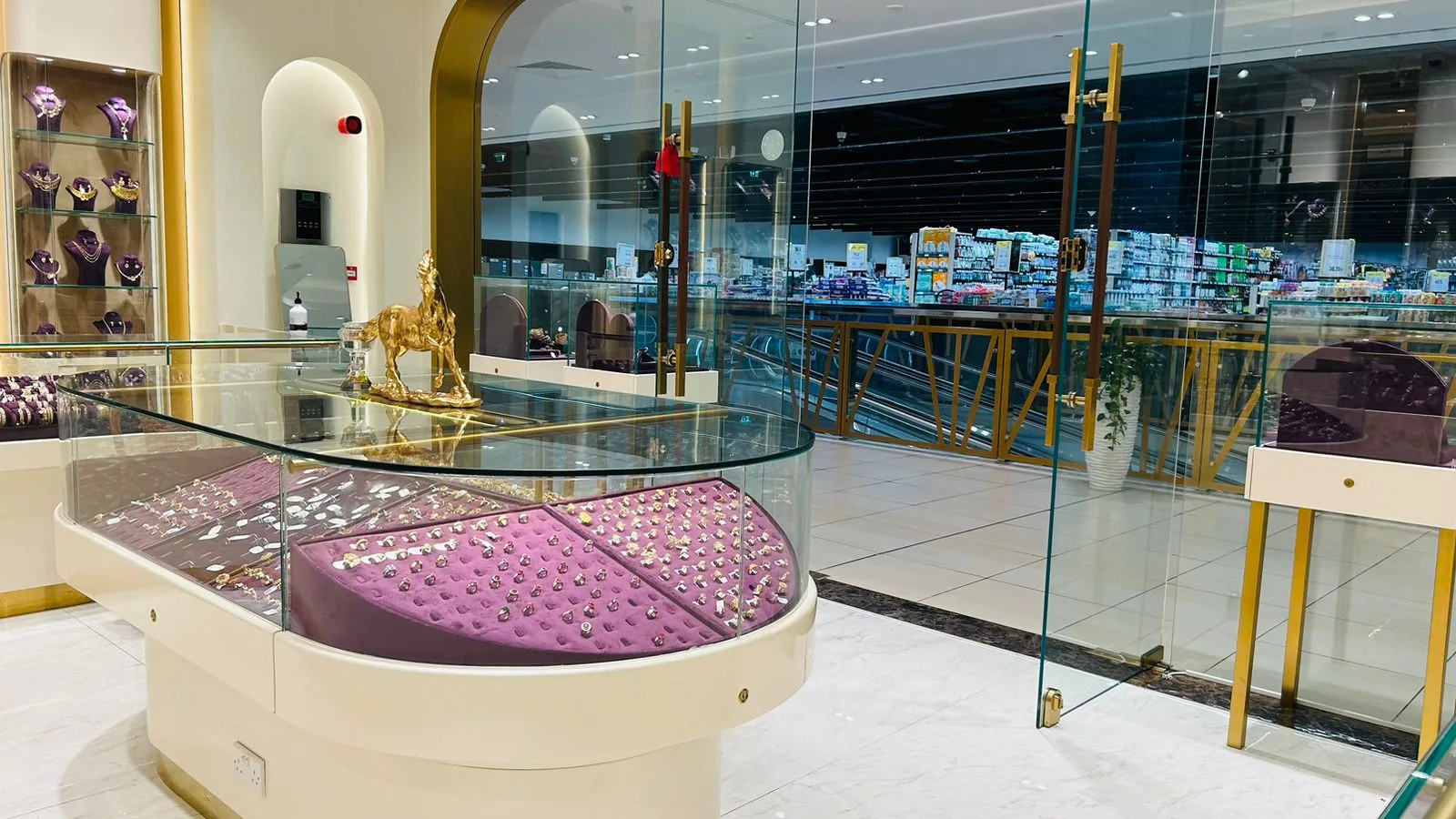 A curved glass display counter at Al Saif Jewellers filled with gold and gemstone rings on purple velvet