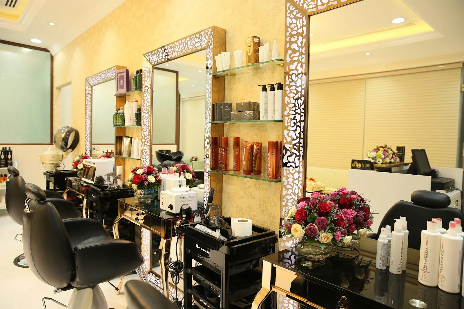 Belle Avenue Beauty Salon styling area with gold-framed mirrors and fresh flowers