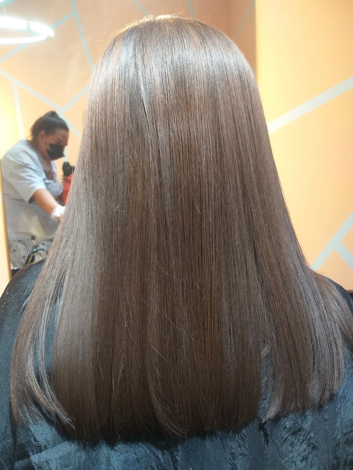 A client's freshly straightened, glossy ash-brown hair at Amirat Al Jamila Ladies Salon