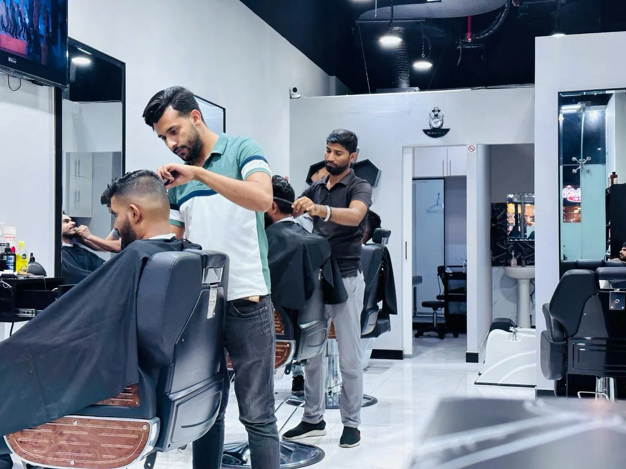 Barbers cutting hair for clients inside Babul Shil Gents Saloon
