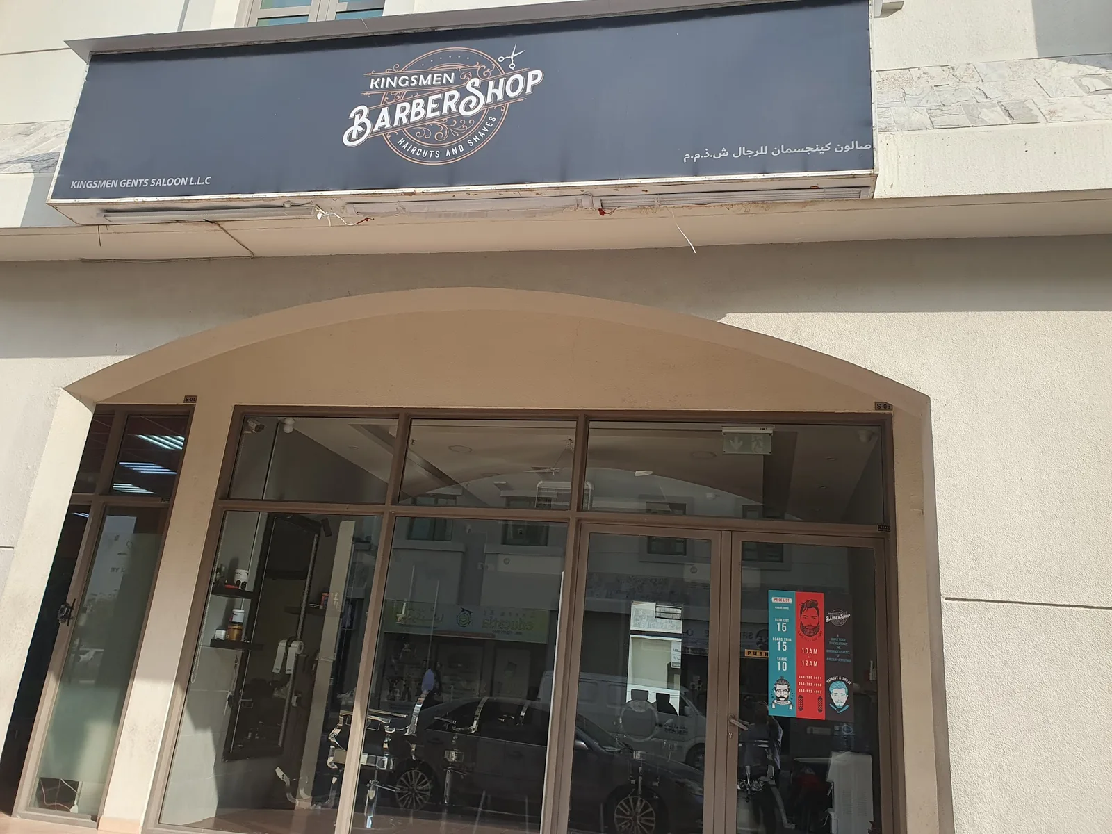 Kingsmen Barbershop storefront with arched entrance and signage in Dubai International City