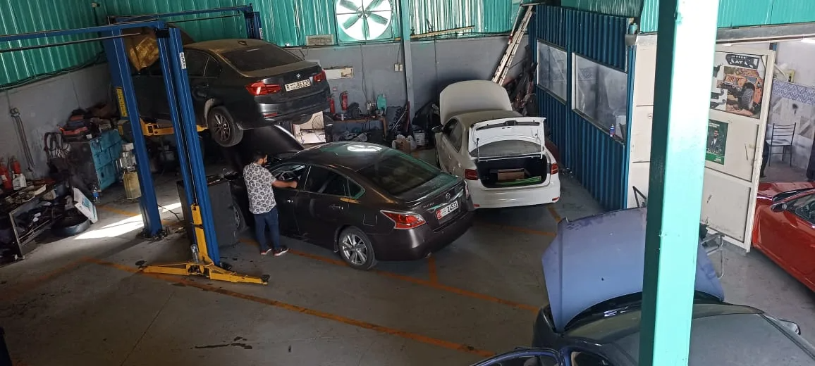 A BMW raised on a lift and a Nissan being serviced beside it across twin service bays in the workshop.
