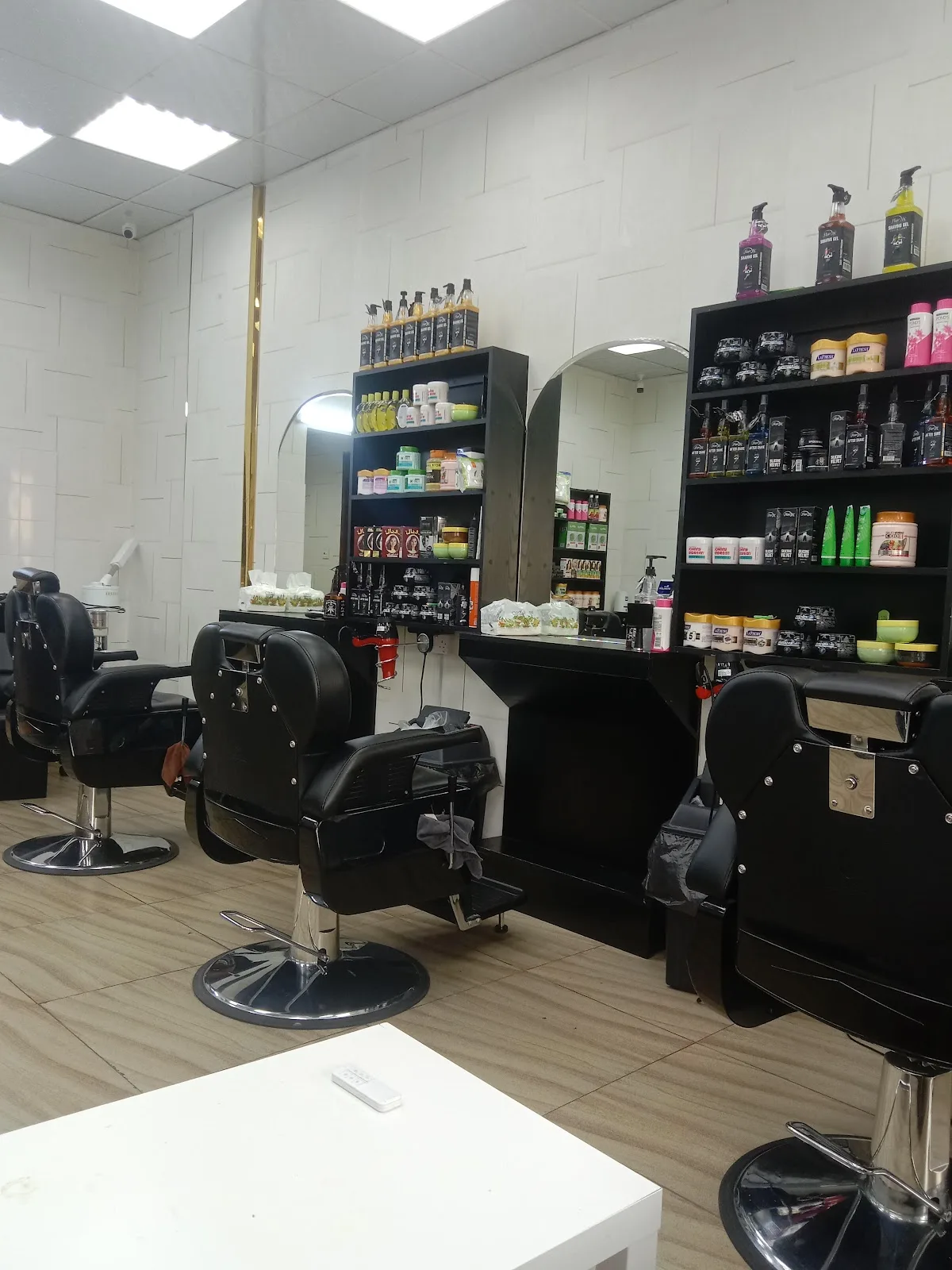 Interior of Blue Paradise Gents Saloon with black barber chairs, arched mirrors and shelves of grooming products