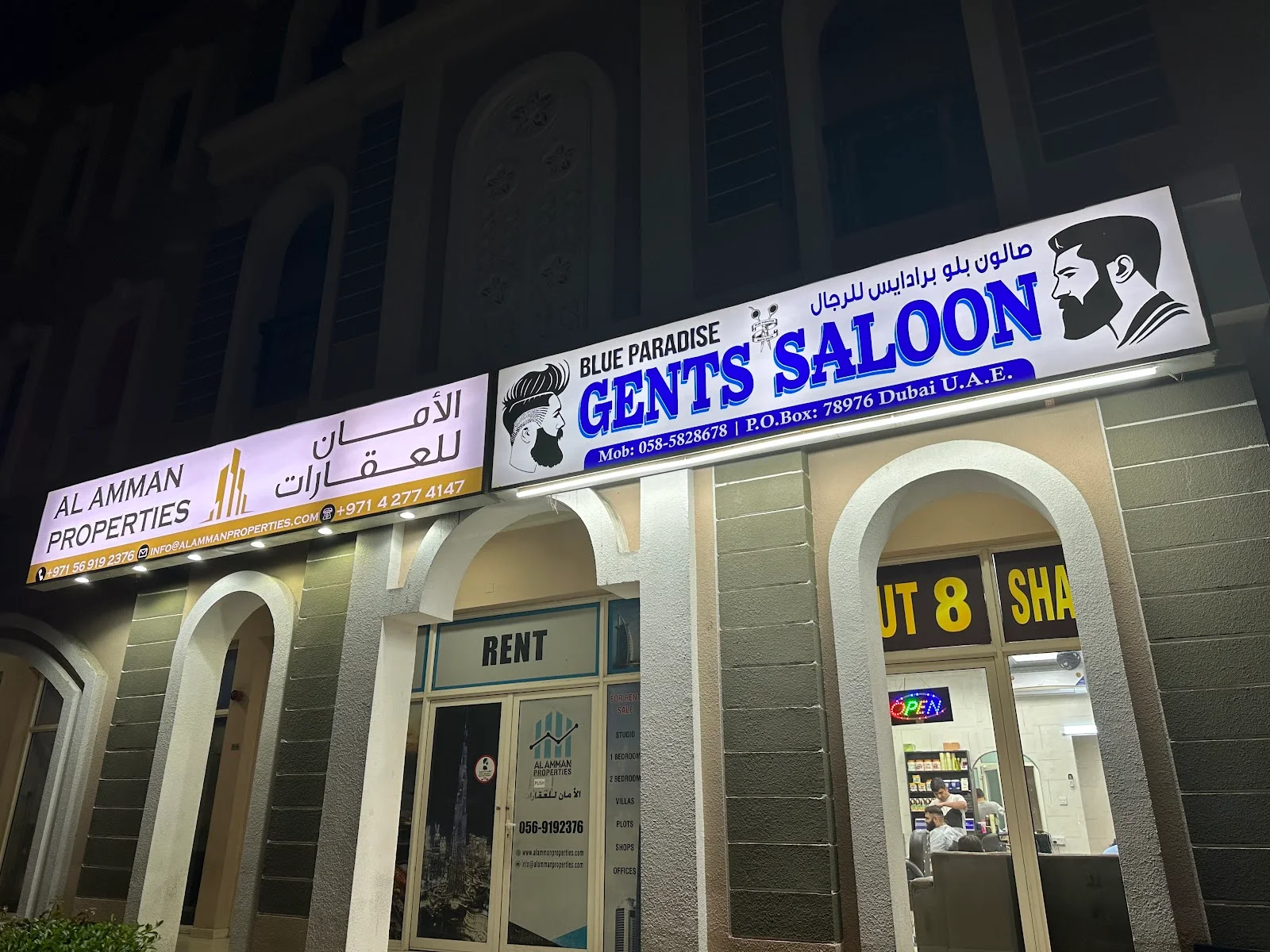 Blue Paradise Gents Saloon illuminated shopfront sign at night in Dubai International City
