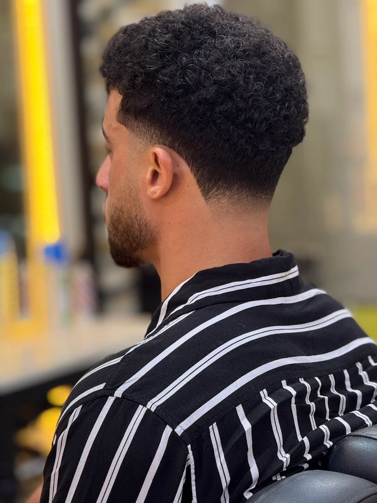 Curly fade with sculpted neckline, rear view