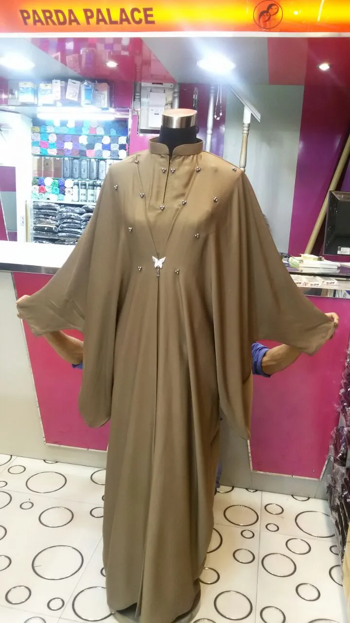 Tan beaded kaftan with a butterfly clasp at Parda Palace