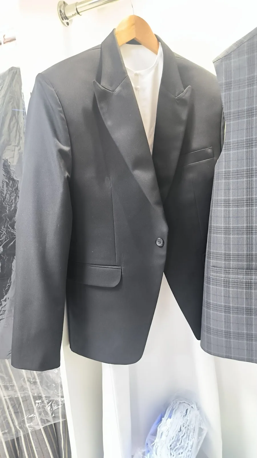 A tailored black single-breasted blazer on a wooden hanger