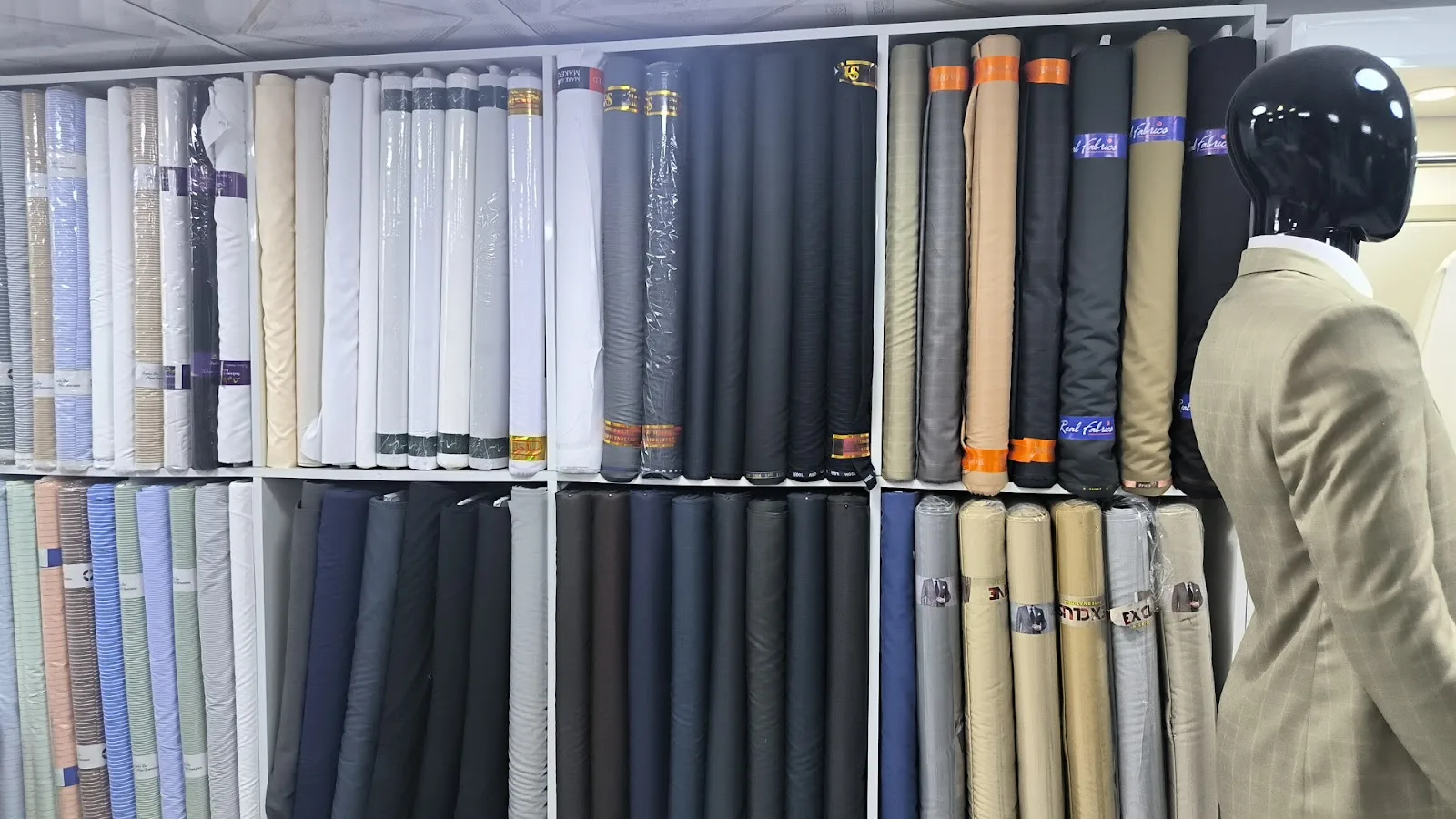 Wall of suiting and shirting fabric rolls inside Qasar Al Ajaz Tailoring in Al Satwa, Dubai