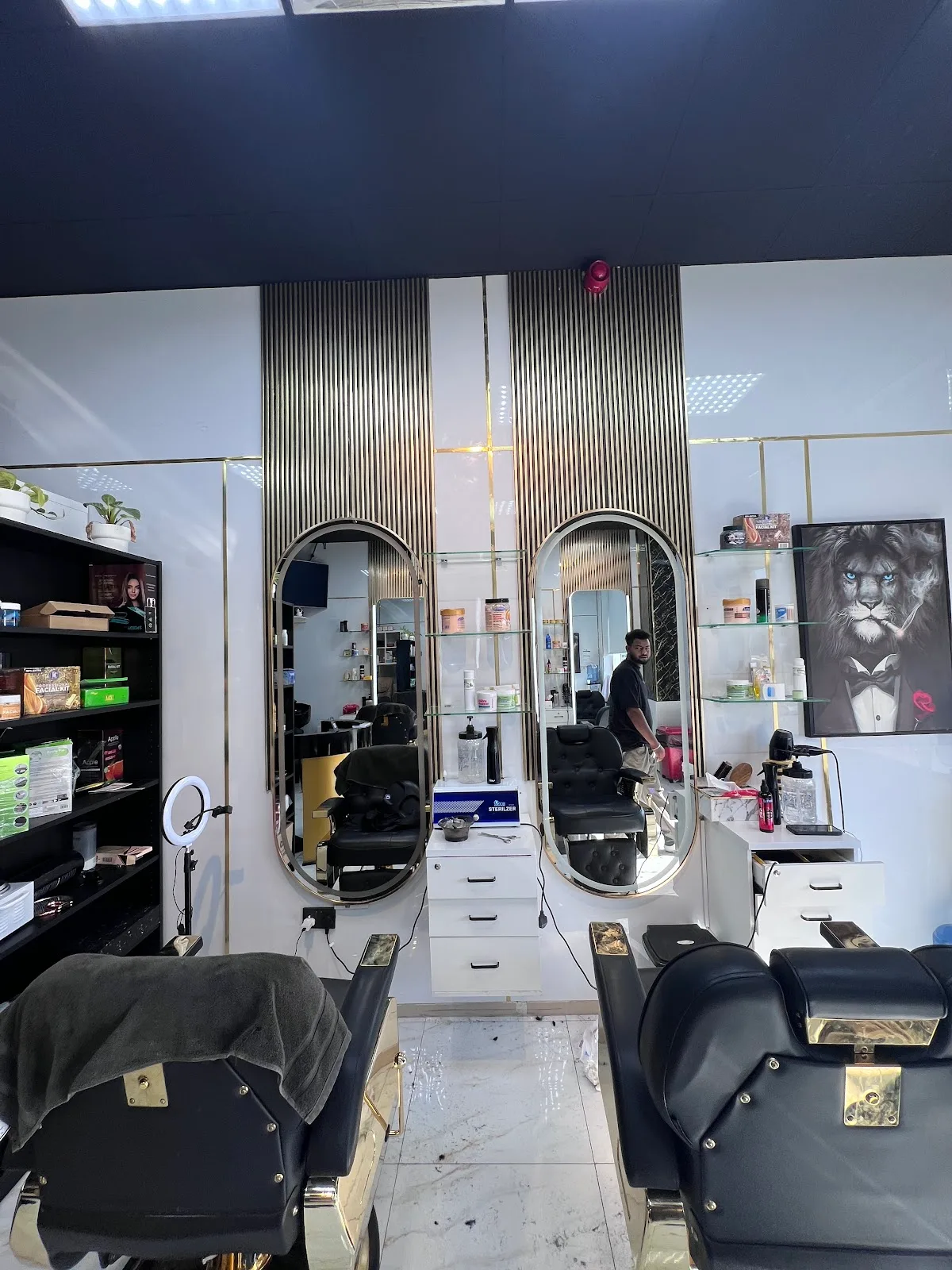 Inside Noor Al Khaima Gents Salon — twin oval gold-framed mirrors, black leather barber chairs and a marble feature wall