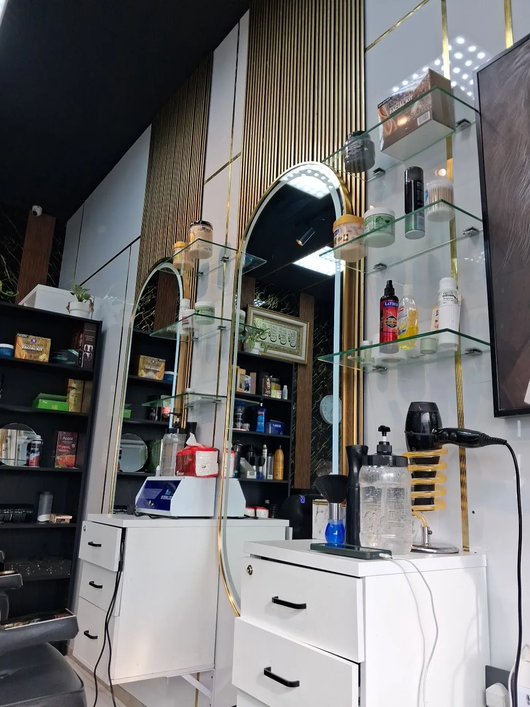 A styling station with a backlit mirror, glass shelves and grooming products at the salon