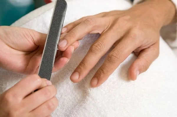 Close-up of a gentleman's manicure being filed on a white towel