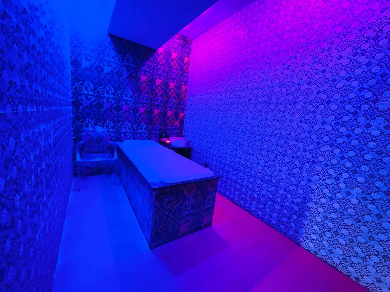 Dimly lit Moroccan bath and massage room with patterned tile walls