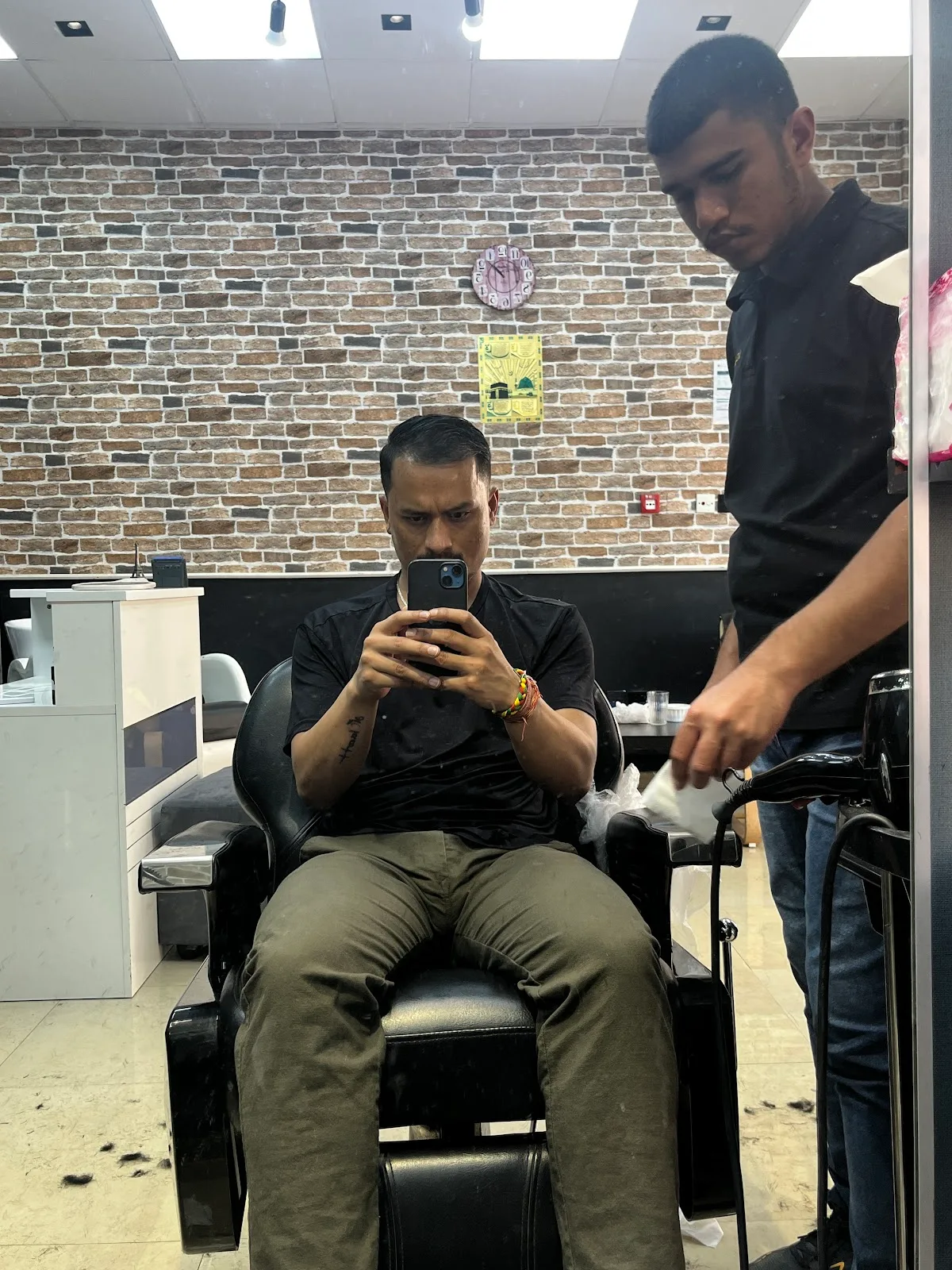 Client seated in the barber chair against an exposed brick wall