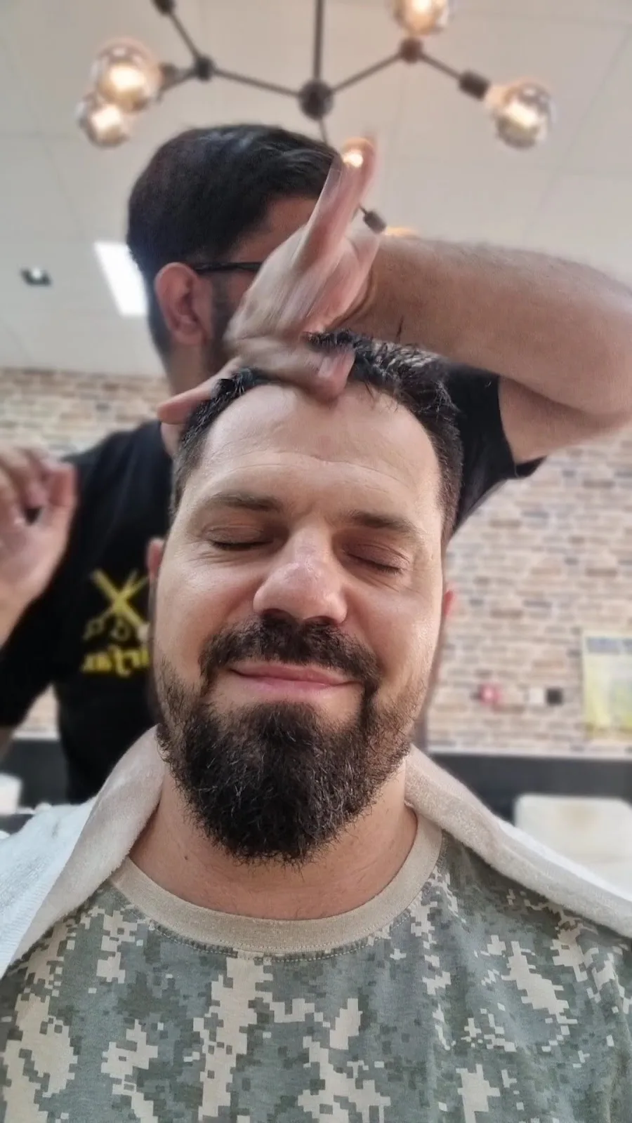 Barber giving a head and styling treatment to a relaxed client