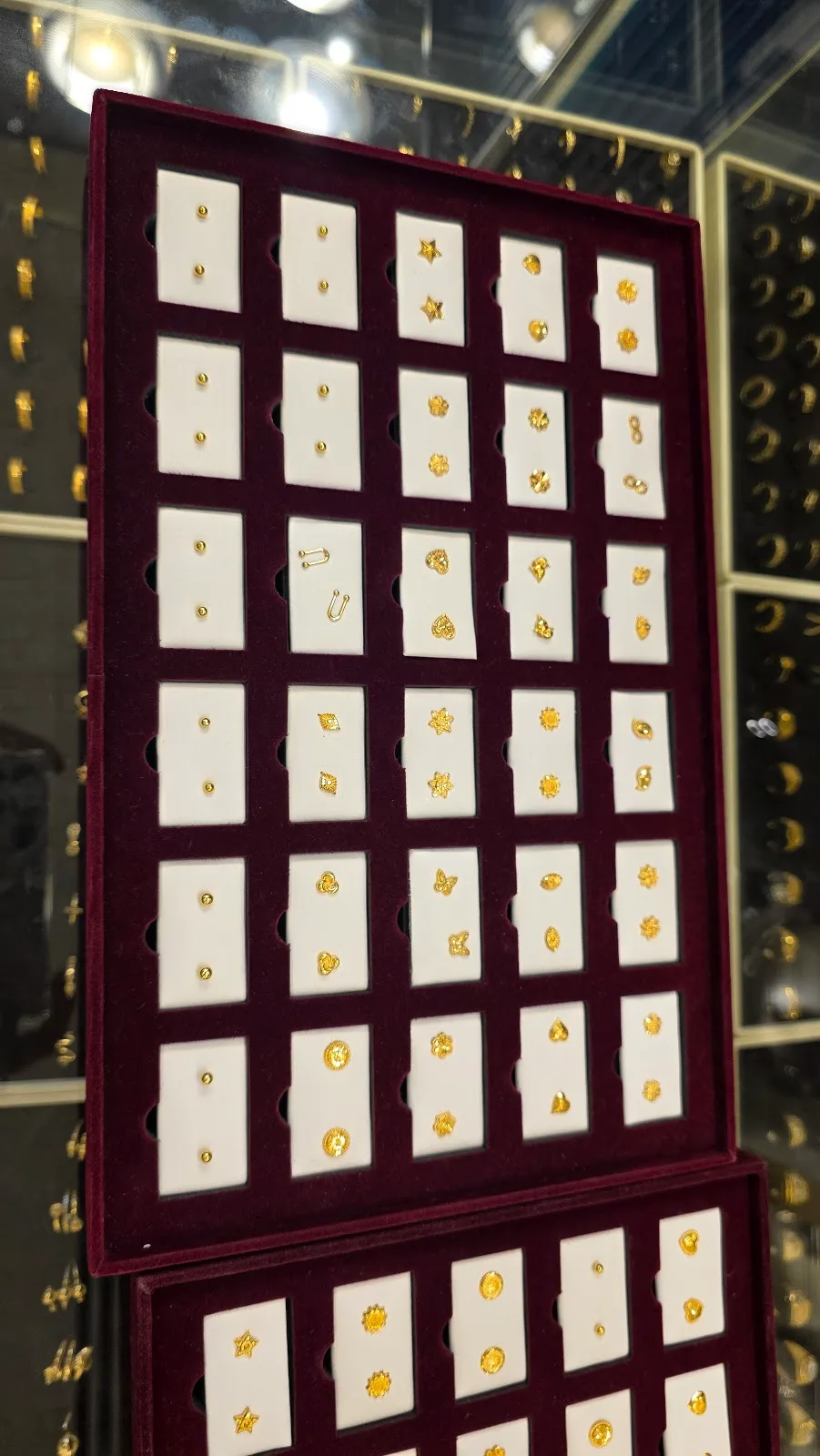 Small gold stud earrings displayed on a tray at Top Pure Jewellery